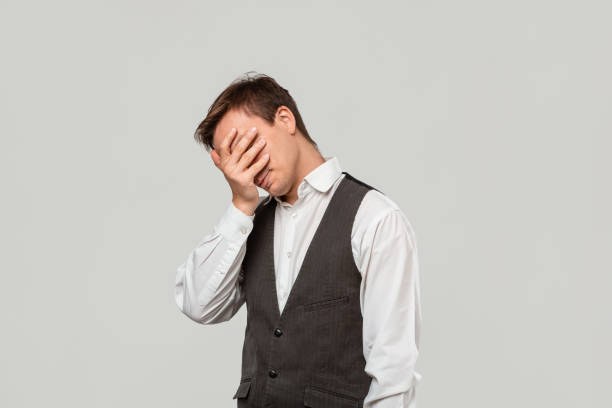istock Handsome man in a white shirt and grey vest clutches head because he faces some problems. 1207302738