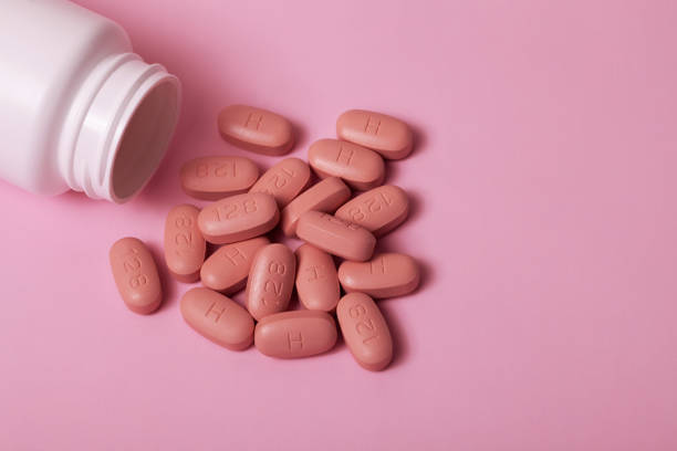 istock Open bottle of hiv therapy pills on pink background 1207303249