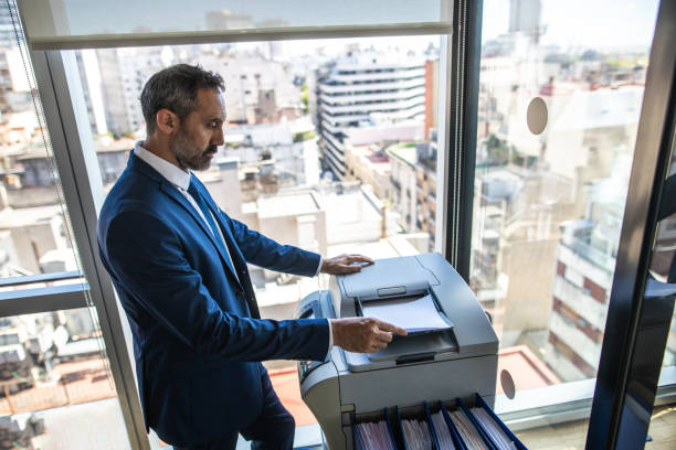 Side view of Latin businessman copying paper document on photocopier machine in office