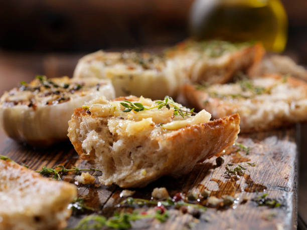 roasted garlic spread on toasted baguette with salt, pepper, thyme and olive oil - crostini imagens e fotografias de stock