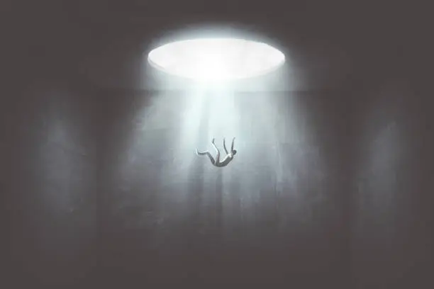 Photo of man falling down from a hole of light, surreal concept