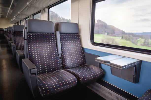 Train interior with empty seats. Swiss modern train wagon Swiss train interior with comfortable chairs, on two rows, a table and nature view on window. Public transport context. Passenger train interior. train interior stock pictures, royalty-free photos & images