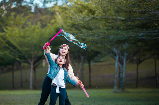 Mother and daughter playing soap bubbles at park