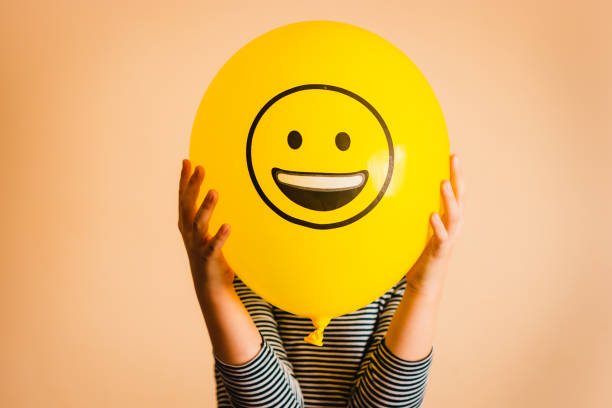 niño sosteniendo globo amarillo en las manos - felicidad ilustraciones fotografías e imágenes de stock
