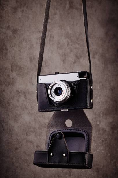 vintage analog rangefinder film camera in leather case hanging in front of a concrete textured wall as background - rangefinder camera imagens e fotografias de stock