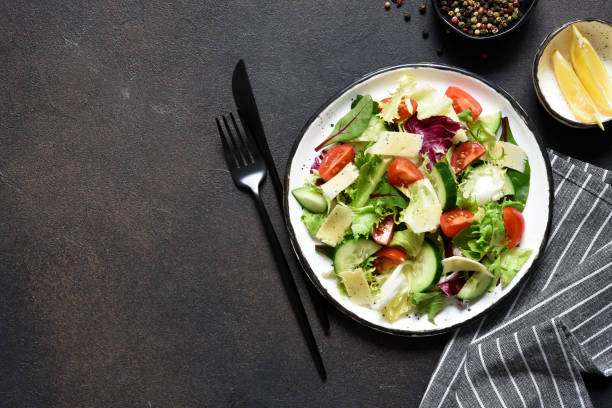 istock Green salad with tomatoes and fried bread on a dark concrete background. Top view with place for text. 1207314607