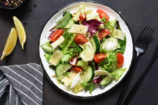 istock Green salad with tomatoes and fried bread on a dark concrete background. Top view with place for text. 1207314655