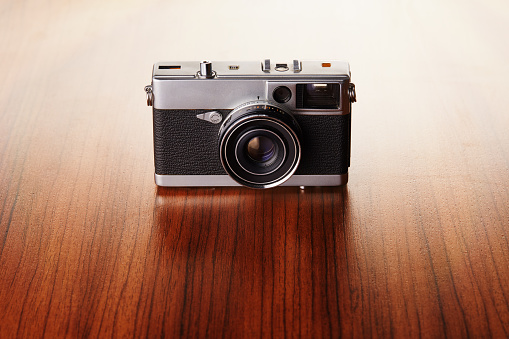 Vintage analog rangefinder film camera on wooden table