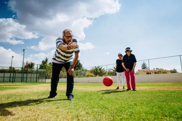 Outdoor activity for vital seniors - Hispanic seniors playing boules in summer. Image with lots of copy space.