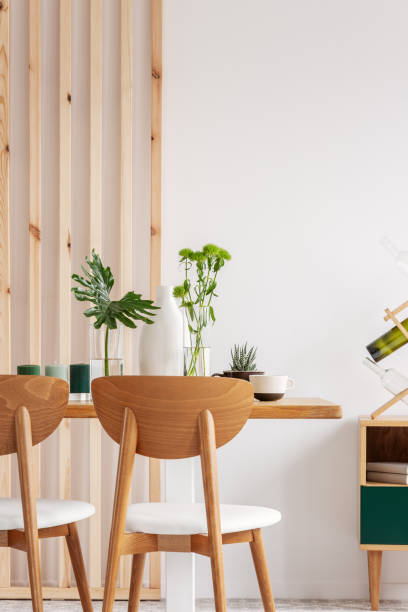 istock Green plants in small vases on long wooden dining table in bright interior 1207316539