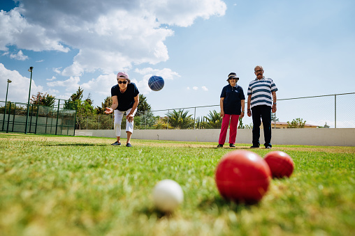 Outdoor activity for vital seniors - Hispanic seniors playing boules in summer. Image with lots of copy space.