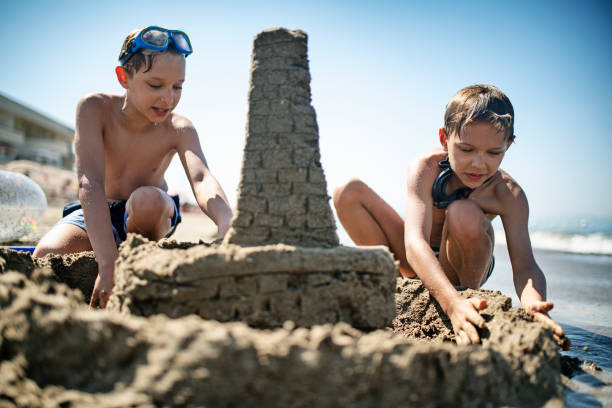 istock Little boys building sandcastle on beach 1207317189