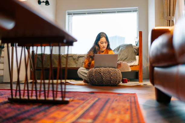 mujer joven usando portátil cómodamente en casa - living will fotografías e imágenes de stock