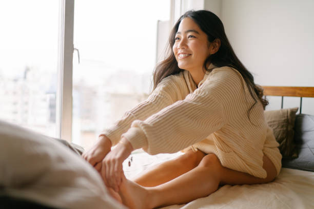 młoda kobieta rozciągając nogi na dzień na łóżku - yoga young adult cheerful happiness zdjęcia i obrazy z banku zdjęć