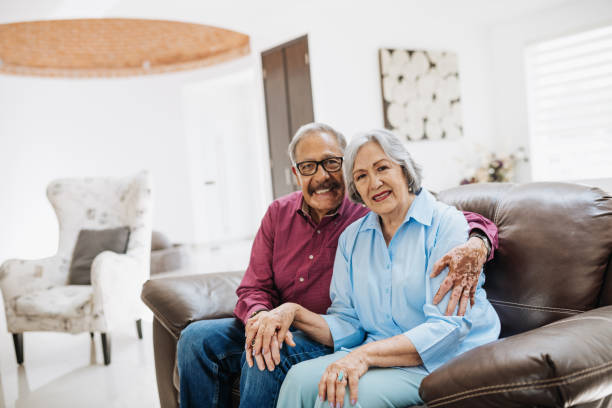 istock Latino senior couple sitting on sofa and smiling 1207318199