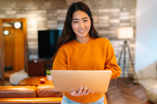 молодая женщина, держащая ноутбук и улыбающаяся для камеры - holding laptop women computer стоковые фото и изображения
