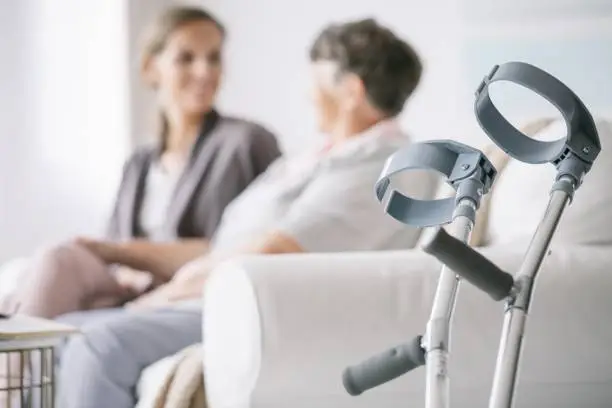 Close-up of older woman's crutches left by the sofa in a nursing home