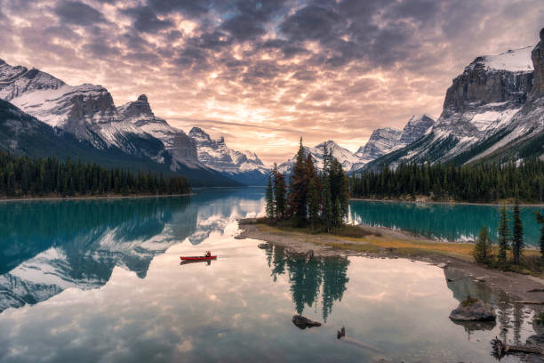 canoa viaggiatore con riflessione sulle montagne rocciose sul lago maligne sull'isola spirit nel parco nazionale di jasper - parco nazionale di jasper foto e immagini stock