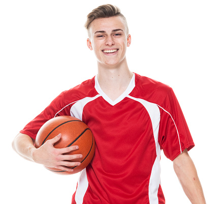 Waist up of aged 16-17 years old caucasian male american football player standing in front of white background wearing soccer uniform who is smiling and holding basketball - ball and playing soccer - sport and using sports ball
