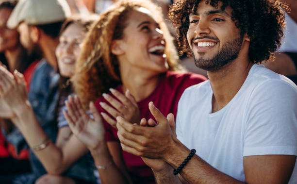 istock Man clapping while watching a soccer match with friends at stadium 1207322800
