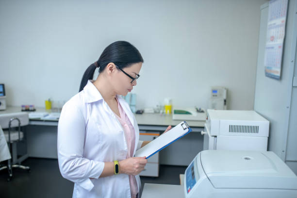 istock Dark-haired technician in eyeglasses reading test results 1207323678