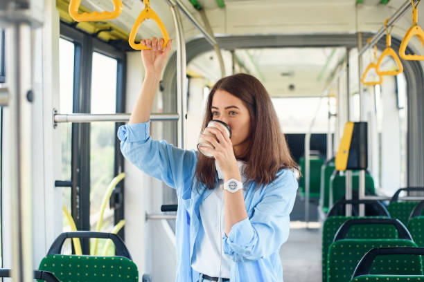 istock Beautiful woman in blue shit drinks coffee while riding in the public transport. 1207323768