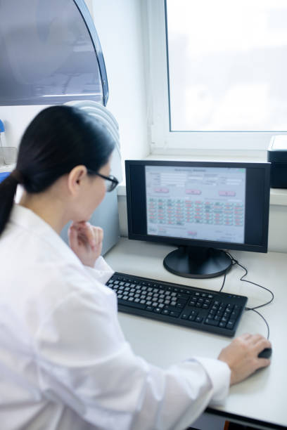 istock Dark-haired doctor in a white robe working on a computer looking thoughtful 1207324919