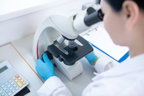 istock Worker of biochemical laboratory looking in microscope 1207325471