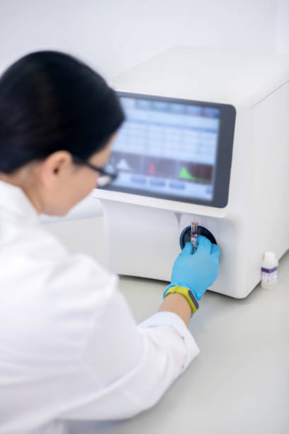 istock Technician in blue gloves pressing the start button of hematological analyzer 1207325499