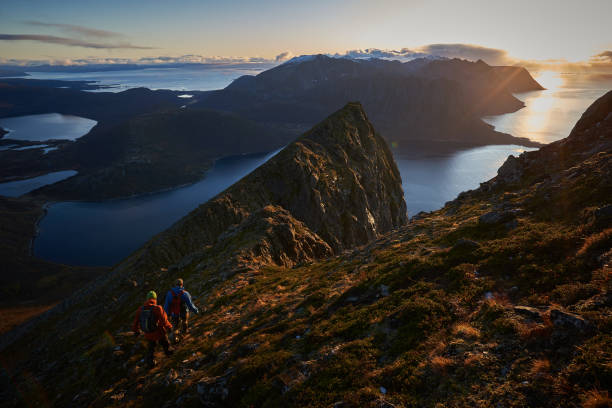 istock Men hiking on a steep mountain in a setting autumn sun. 1207329712