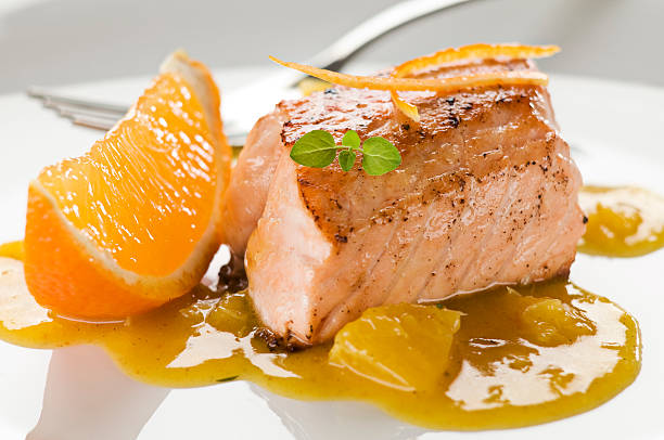 Picture of a salmon dish with orange sauce and garnish stock photo