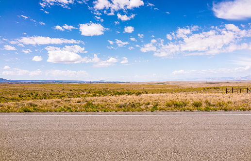 A horizon of rural land in Utah, USA, with the asphalt surface of the highway in the foreground.