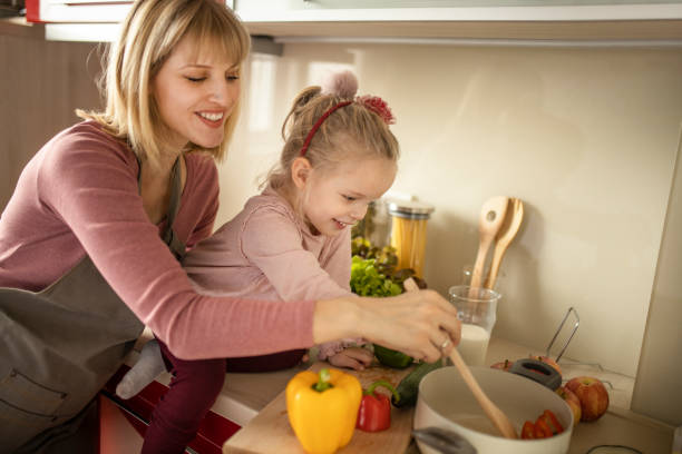 istock Mother and daughter preparing food in modern kitchen 1207341329