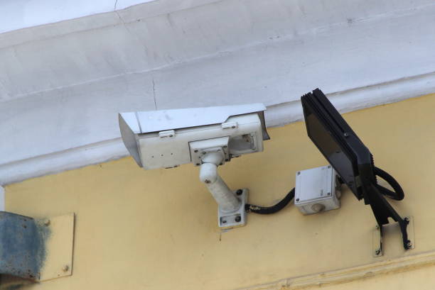 istock Surveillance camera mounted on tiled wall of house 1207341687
