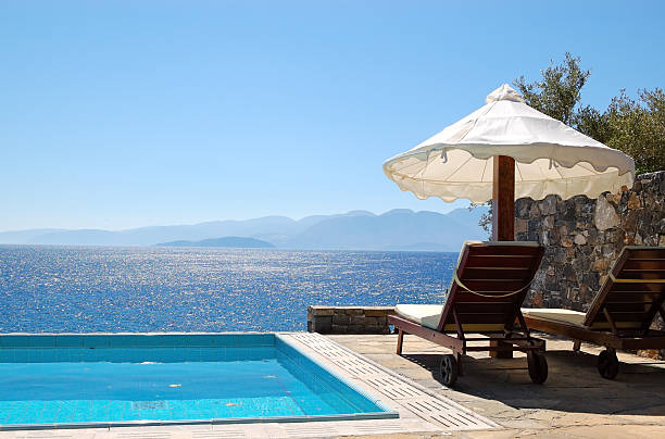 Sun loungers with mattresses and sun umbrellas stand by the pool. Hotel Amanzoe, Greece. High quality photo