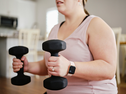 A woman exercising in her home with hand weights.