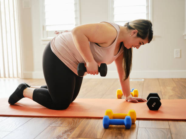 家庭で運動体重を使用する女性 - real bodies ストックフォトと画像