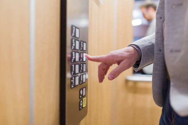 istock Close up of businessman pressing button in modern elevator. 1207349676