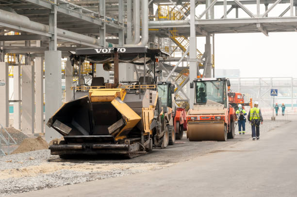 Paving machine placing a layer of asphalt Tobolsk, Russia - July 23. 2019: Sibur company. Construction of plant on processing of hydrocarbonic raw materials. A paver finisher, asphalt finisher or paving machine placing a layer of asphalt hard bituminous coal stock pictures, royalty-free photos & images