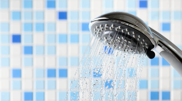 istock Shower head with flowing water stream in blue bathroom 1207353111