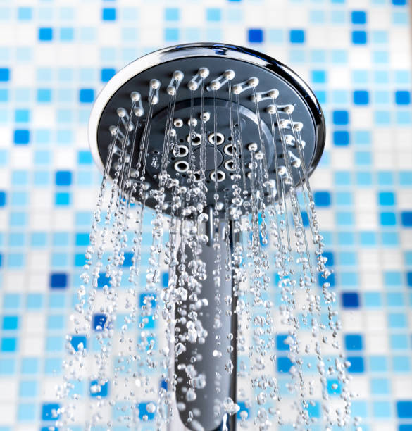 istock Shower head with flowing water stream in blue bathroom. Close-up. 1207353120