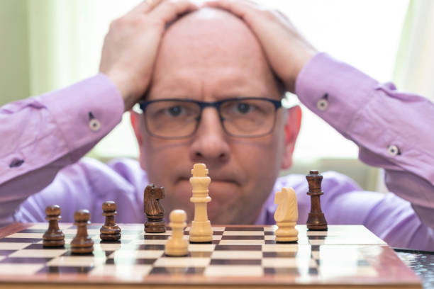 istock The man looks thoughtfully at the chess pieces and holds his head. 1207355448