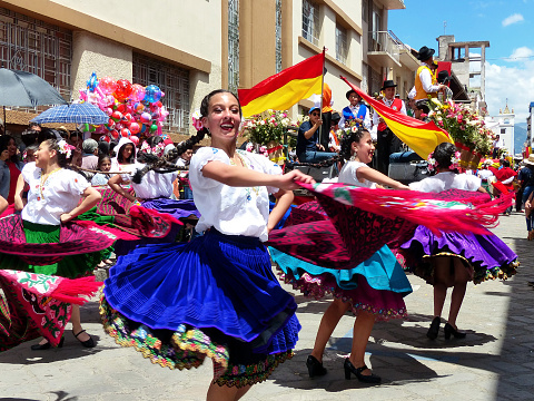 Cuenca, Ecuador - April 11, 2019: Folk dancers in costumes typical for Azuay province as cholas cuencanas and with province flags at traditional parade for day foundation of Cuenca