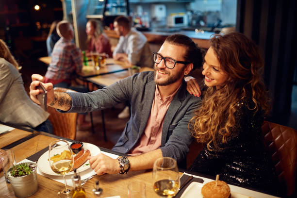 nette kaukasische modische paar sitzt im restaurant beim abendessen und selfie. - photographing smart phone friendship photo messaging stock-fotos und bilder