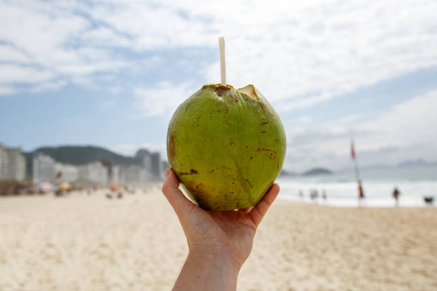 istock Fresh green coconut with a straw on a beach background. 1207358200