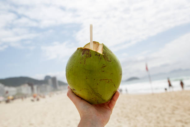 istock Fresh green coconut with a straw on a beach background. 1207358202
