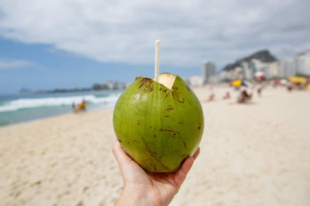 istock Fresh green coconut with a straw on a beach background. 1207358210