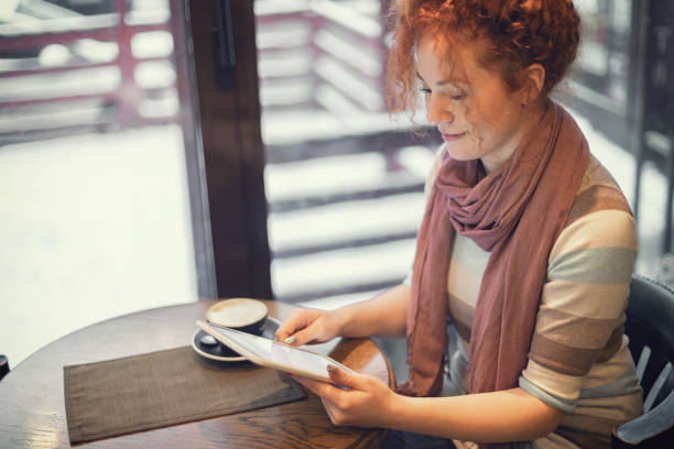 istock Woman sitting at a cafe and working on digital tablet 1207358392