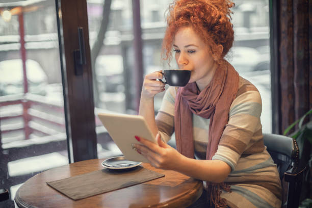 istock Woman sitting at a cafe and working on digital tablet 1207359020