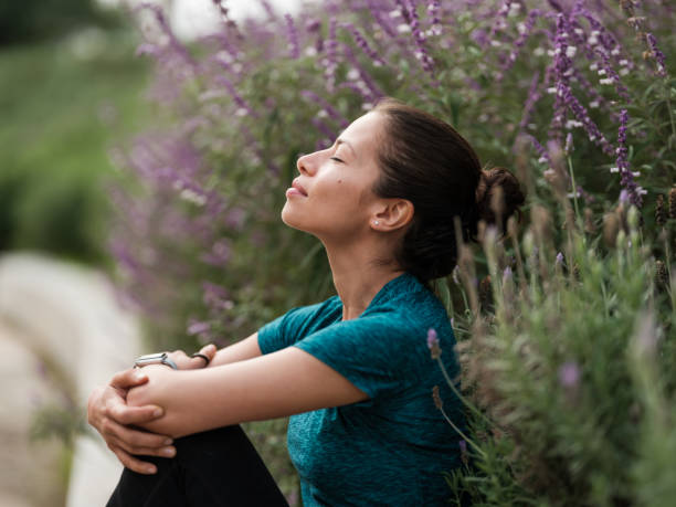 mujer latina relajándose junto a las flores - meditating fotografías e imágenes de stock